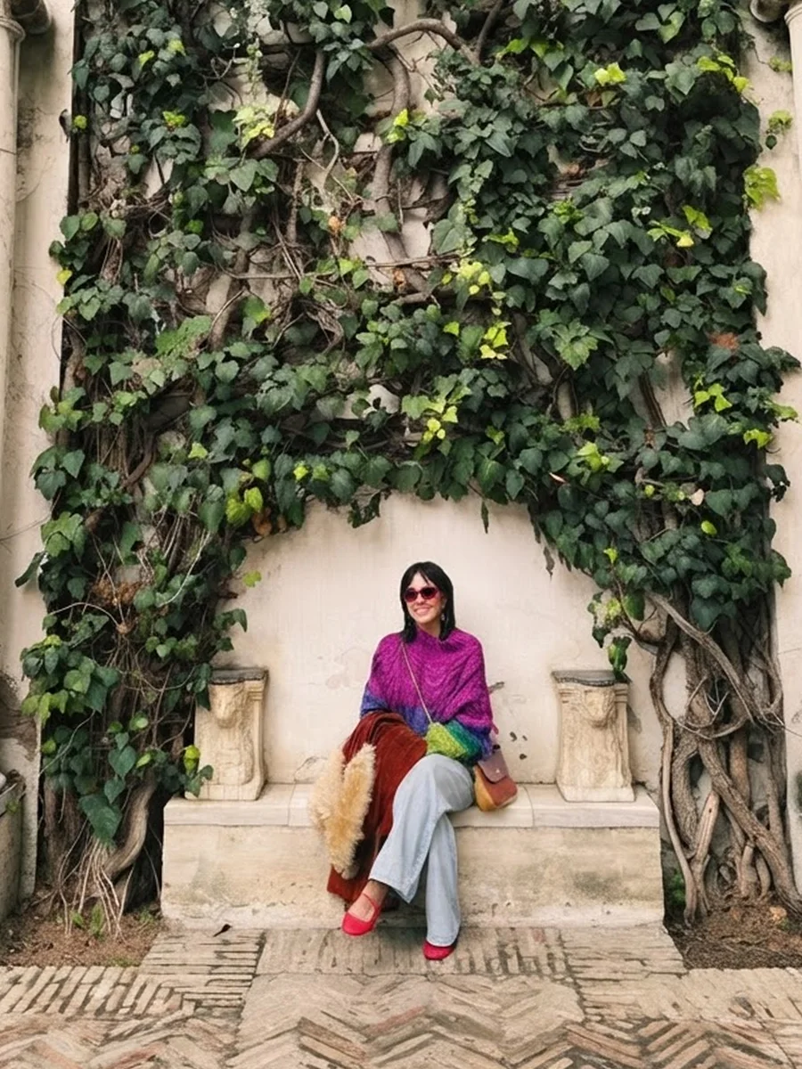 Karen sitting on a stone bench under an ivy-covered wall between two marble columns