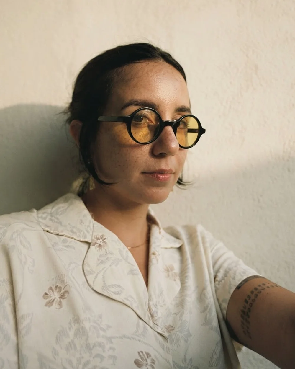 Karen Ramos in warm late-afternoon light, wearing round glasses with yellow lenses